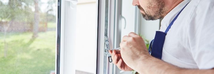 Person repariert Fenster mit Schraubendreher
